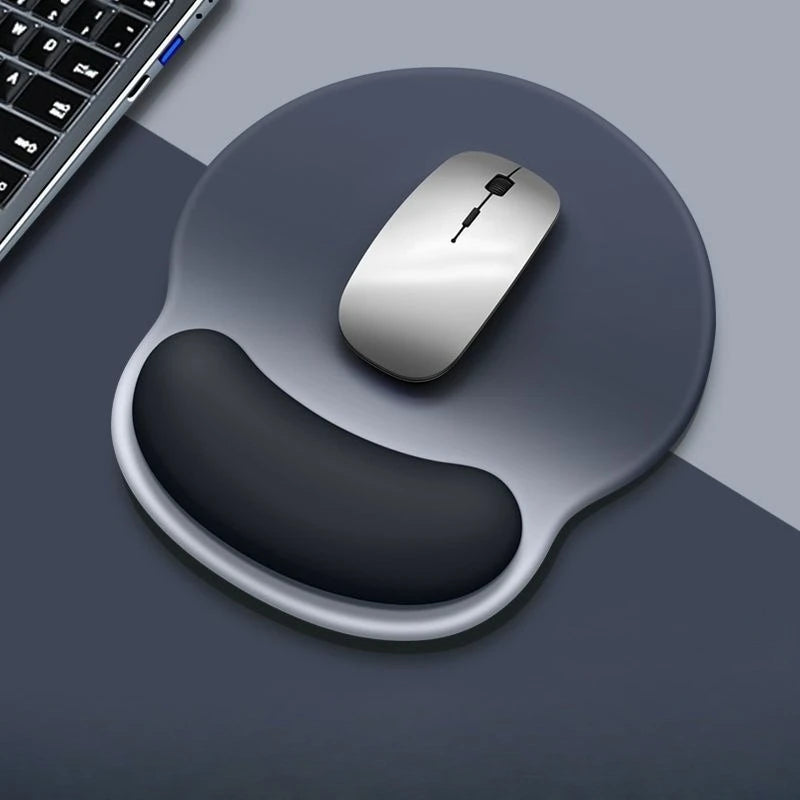 Gray mouse on a dark gray mouse pad with wrist rest, next to a keyboard on a gray surface.